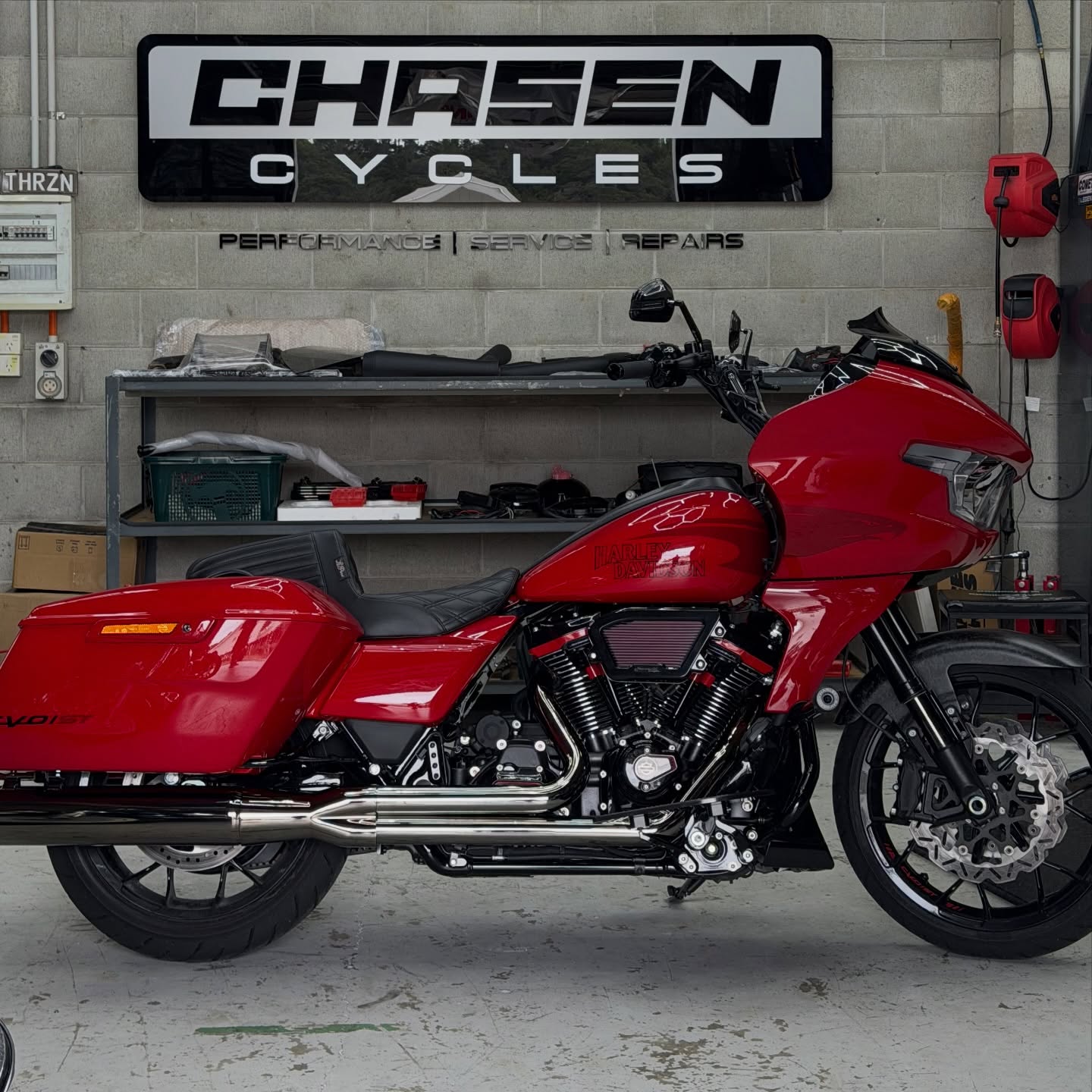 Bright red Harley-Davidson Road Glide bagger under the Chasen Cycles sign