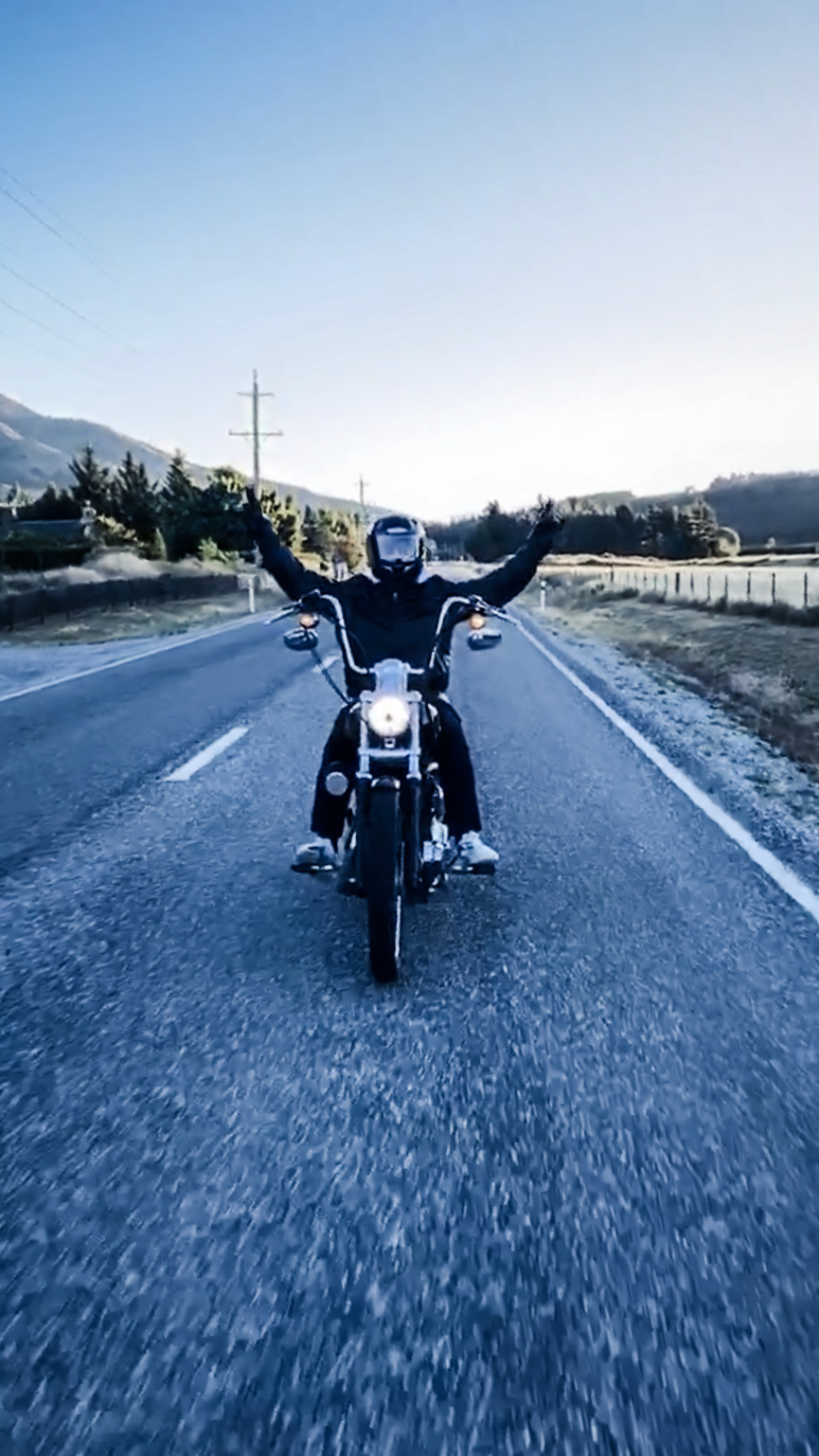Harley rider on a frosty open road, arms out, helmet on